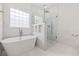 Elegant bathroom featuring a freestanding tub and glass-enclosed shower, all adorned with sleek, white tiles at 293 Hillsborough Dr., Conway, SC 29526