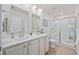 Bright bathroom featuring double sinks, white cabinets, tile floors, and a glass-door shower at 351 Logan St., Little River, SC 29566