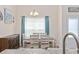 Dining room table with seating for six, blue curtains, and a wooden credenza with storage at 351 Logan St., Little River, SC 29566