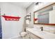 Bathroom showcasing a modern vanity, sink, mirror, and decorative red nautical shelf at 4504 S Ocean Blvd. # A, North Myrtle Beach, SC 29582
