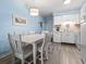 View of the dining area featuring light blue paneled walls, white table and chairs, and a decorative light fixture at 5000 N Ocean Blvd. # B-1, North Myrtle Beach, SC 29582