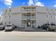 Three story condominium building with gray siding, white railings, and clearly marked compact parking spaces at 5000 N Ocean Blvd. # B-1, North Myrtle Beach, SC 29582