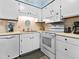 A kitchen area featuring white cabinets, appliances, light countertops, and modern flooring at 5000 N Ocean Blvd. # B-1, North Myrtle Beach, SC 29582