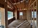 Interior view of a new home under construction, highlighting the exposed wood framing and a window with a neighborhood view at 6001 - 5142 S Kings Hwy., Myrtle Beach, SC 29575