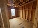 Framed bedroom under construction, showcasing exposed beams, electrical wiring, and a view from the window of nearby houses at 6001 - 5142 S Kings Hwy., Myrtle Beach, SC 29575