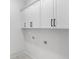 Bright laundry room features white cabinets, black handles and modern hookups at 100 Serenity Point Dr., Little River, SC 29566