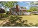 The backyard has a green lawn, brick home, deck, and tall trees on a sunny day at 124 Windmeadows Dr., Conway, SC 29526