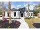 Striking home features a white exterior with black accents, landscaped yard, and inviting walkway to the front door at 1559 Old Tram Rd., Little River, SC 29566