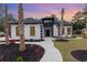 Striking home features a white exterior with black accents, landscaped yard, and inviting walkway to the front door at 1559 Old Tram Rd., Little River, SC 29566