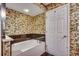This bathroom offers a tub, floral wallpaper, and white door at 1625 S Ocean Blvd. # 1604, North Myrtle Beach, SC 29582