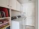 Well-lit laundry room with white washer and dryer, cabinetry, hanging rack and game storage at 1856 Melville Ct., Little River, SC 29566