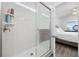 A modern glass shower enclosure with white tiled walls and floors connects to the primary bedroom at 2602 Holly Dr., North Myrtle Beach, SC 29582