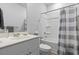 Well-lit bathroom featuring a white vanity, toilet and a shower-tub with grey striped shower curtain at 295 Brackish Dr. # 673, Myrtle Beach, SC 29588
