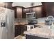Well-equipped kitchen featuring a stainless steel refrigerator, range, dark wood cabinets, and granite countertops at 305 Blue Rock Dr., Longs, SC 29568