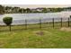 A picturesque lake view featuring a lush green lawn and secure black fencing at 388 Carriage Lake Dr., Little River, SC 29566