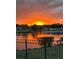 A vibrant sunrise reflecting on a lake, seen through a black metal fence at 388 Carriage Lake Dr., Little River, SC 29566