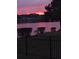 Stunning sunset over a lake with tranquil reflections, viewed from a black metal fence at 388 Carriage Lake Dr., Little River, SC 29566