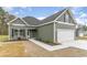 View of the exterior with a two-car garage, landscaped front yard, and green siding at 4010 Macks Rd, Aynor, SC 29511
