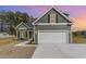 Charming home exterior at dusk featuring a two-car garage, landscaped front yard, and green siding at 4010 Macks Rd, Aynor, SC 29511