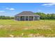 A gray, one-story house with a covered patio overlooking a large green backyard, perfect for outdoor enjoyment at 4022 Macks Rd, Aynor, SC 29511
