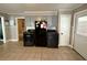 Laundry area with gray cabinets above modern washer and dryer set next to a black refrigerator with door to exterior at 408 South Farr Ave., Andrews, SC 29510