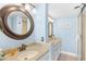 Charming bathroom with double vanity, white cabinets, stone counter tops, and round framed mirror at 4311 S Ocean Blvd. # 701, North Myrtle Beach, SC 29582
