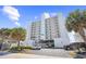 Exterior shot of a tall, white condominium building with multiple balconies, palm trees, and convenient parking spaces at 4311 S Ocean Blvd. # 701, North Myrtle Beach, SC 29582