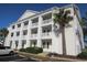 Three-story condo building featuring white siding, columned balconies, and a palm tree in the yard at 5020 Windsor Green Way # 302, Myrtle Beach, SC 29579