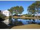 Scenic pond view reflecting the condo building and surrounding trees under a bright blue sky at 5020 Windsor Green Way # 302, Myrtle Beach, SC 29579