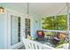 This covered porch features a porch swing, a ceiling light, wicker furniture, and a side view of the yard at 504 A S 19Th Ave. S, North Myrtle Beach, SC 29582