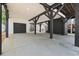 View of an open carport with concrete flooring, dark beams, and a matching black garage door on the side at 6001 S Kings Hwy., Myrtle Beach, SC 29575