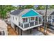 Attractive raised beach house features a blue roof and inviting porch with black railings at 6001 S Kings Hwy., Myrtle Beach, SC 29575