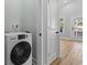 Laundry room with a modern washing machine, white walls, and wood-look flooring at 6001 S Kings Hwy., Myrtle Beach, SC 29575