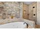Luxurious bathroom featuring a soaking tub, stone walls, and separate glass-enclosed shower at 8008 Mcsweeney Ct., Myrtle Beach, SC 29588