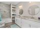 Bright bathroom features double vanity with granite counters, round mirrors, and tiled shower with built-in shelves at 801 Celene Ct., Myrtle Beach, SC 29579