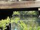 Unique view of a peaceful river framed by weathered wooden beams and lush foliage, creating a serene atmosphere at 1465 Dirty Branch Rd., Conway, SC 29527