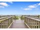 Wooden walkway leads to the beach with a clear view of the ocean and sky, inviting beach days at 2000 N Ocean Blvd. # 502, Myrtle Beach, SC 29577