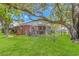 Spacious backyard with green lawn, trees, and a brick house with a screen porch at 311 Surfside Dr., Surfside Beach, SC 29575