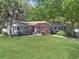 Charming home featuring a lush green lawn, mature trees, and a vibrant red front door creating a welcoming entrance at 412 43Rd Ave. N, Myrtle Beach, SC 29577