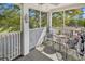 View of a screened porch with chairs, a table, and golf clubs in the corner at 4430 Eastport Blvd. # L15, Little River, SC 29566