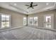 Spacious bedroom featuring plush gray carpet, a tray ceiling, and an abundance of natural light from large windows at 468 Saint Julian Ln., Myrtle Beach, SC 29579