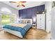 Comfortable bedroom featuring a large window, wood floors, a ceiling fan, and a navy accent wall at 4787 Wild Iris Dr. # 101, Myrtle Beach, SC 29577
