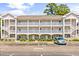 Three-story condo building featuring white trim, multiple balconies, parking, and a well-maintained landscape at 4787 Wild Iris Dr. # 101, Myrtle Beach, SC 29577