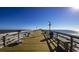 Wooden pier with benches and railings extending over the ocean under a clear blue sky at 532 Duvall St., Longs, SC 29568