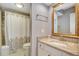 Bathroom with a decorative mirror, granite vanity, and shower with patterned curtain at 5507 N Ocean Blvd. # 105, Myrtle Beach, SC 29577