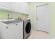 Well-lit laundry room featuring a front-load washer and dryer with ample storage in the white cabinets above at 736 Lalton Dr., Conway, SC 29526