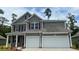 Charming two-story home featuring a two-car garage, gray siding, and crisp white trim details at 877 Ireland Dr., Longs, SC 29568