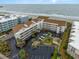 Aerial view of condominiums by the ocean, featuring ample parking and lush tropical landscaping at 9581 Shore Dr. # 223, Myrtle Beach, SC 29572