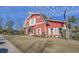 Exterior of a red barn-style clubhouse featuring white trim, shutters, professional landscaping, and ample parking at 1004 Harvester Circle # 1004, Myrtle Beach, SC 29579