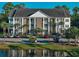 Charming condo building with brick accents, white columns, and lush landscaping overlooking a serene pond at 106 Birch N Coppice Dr. # 2, Surfside Beach, SC 29575